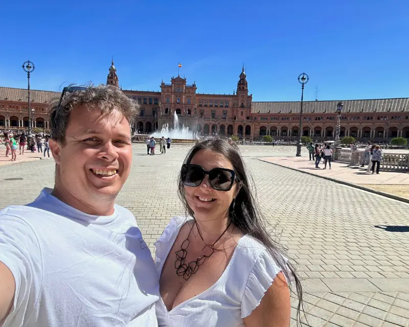 Heidi and Jethro smiling in front of the Plaza de España fountain and palace in Seville