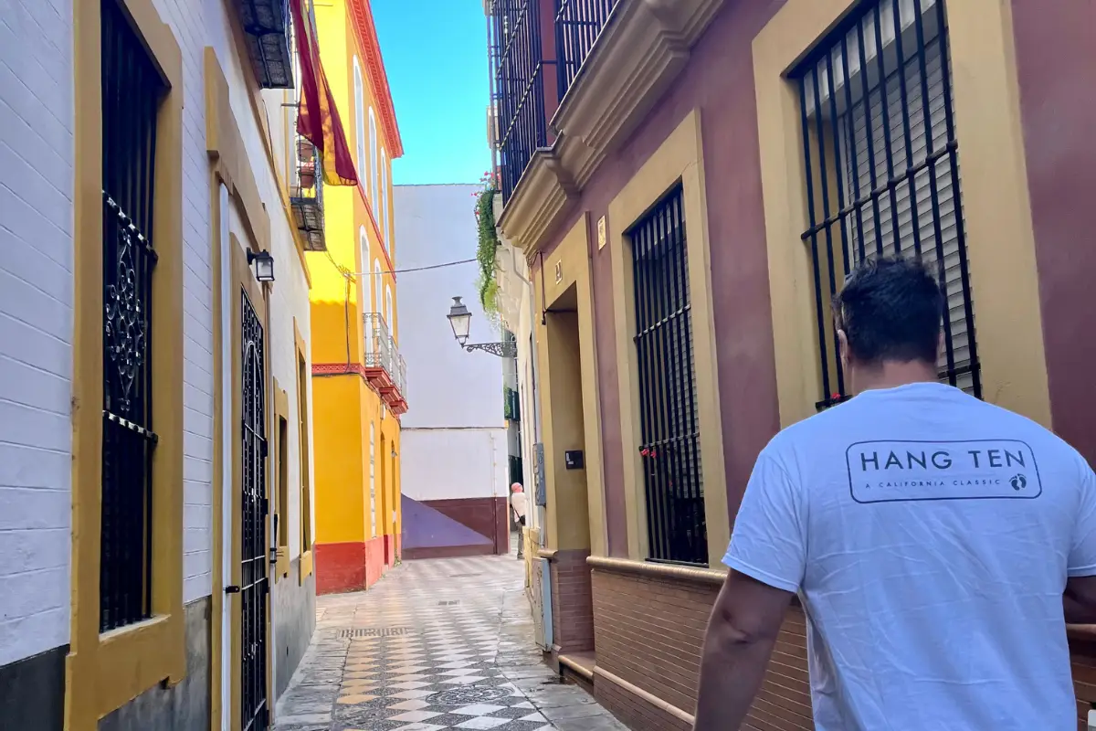 Pedestrians walking through Seville's old town on a sunny day