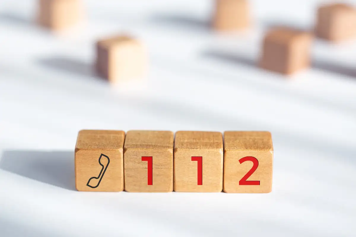 Four wooden blocks depicting one phone and the numbers 112, Spain's emergency number.