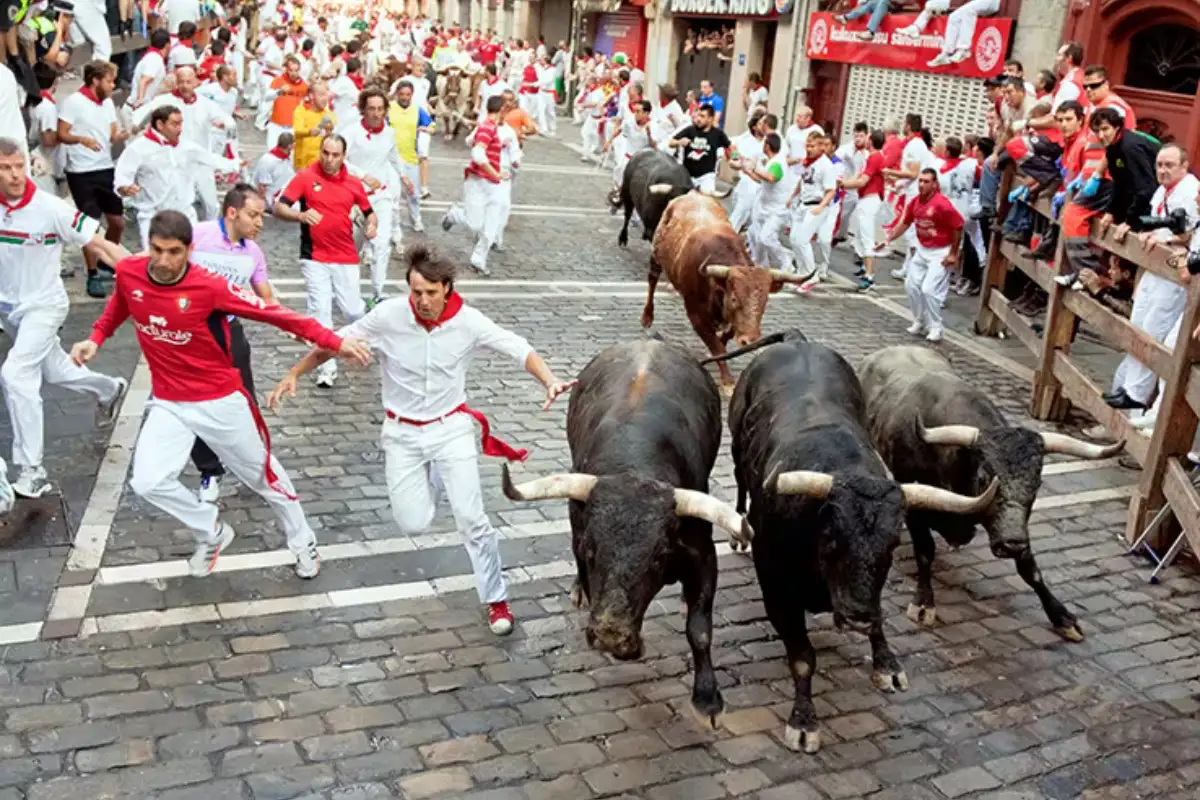 Runners sprinting ahead of bulls through the narrow streets of Pamplona at San Fermin
