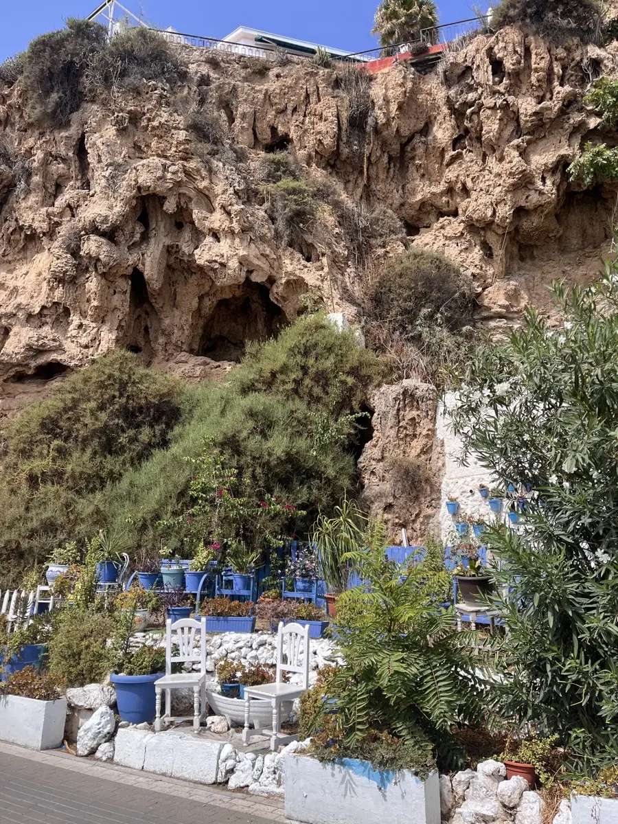 A cliffside garden of blue-painted chairs and potted plants built into the sandstone caves above La Carihuela in Torremolinos