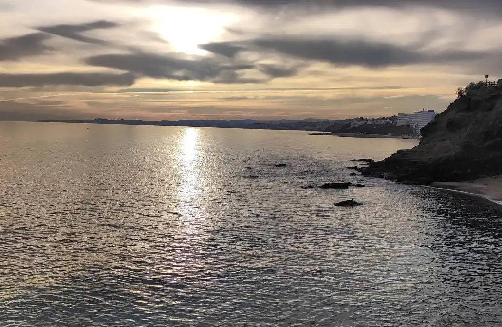 Benalnatura beach at dusk with moody clouds and calm water on the Benalmadena coast