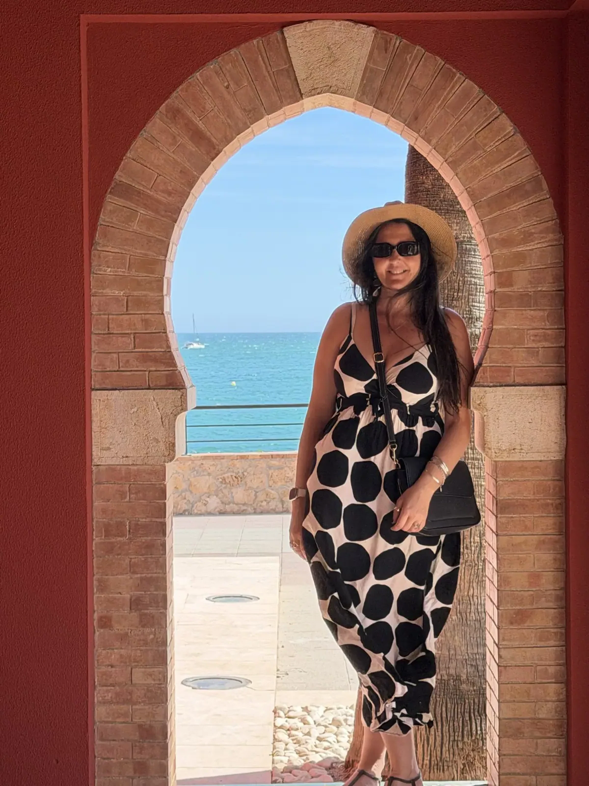 Heidi framed in a Moorish arch at Castillo de Bil-Bil, with the Mediterranean behind her