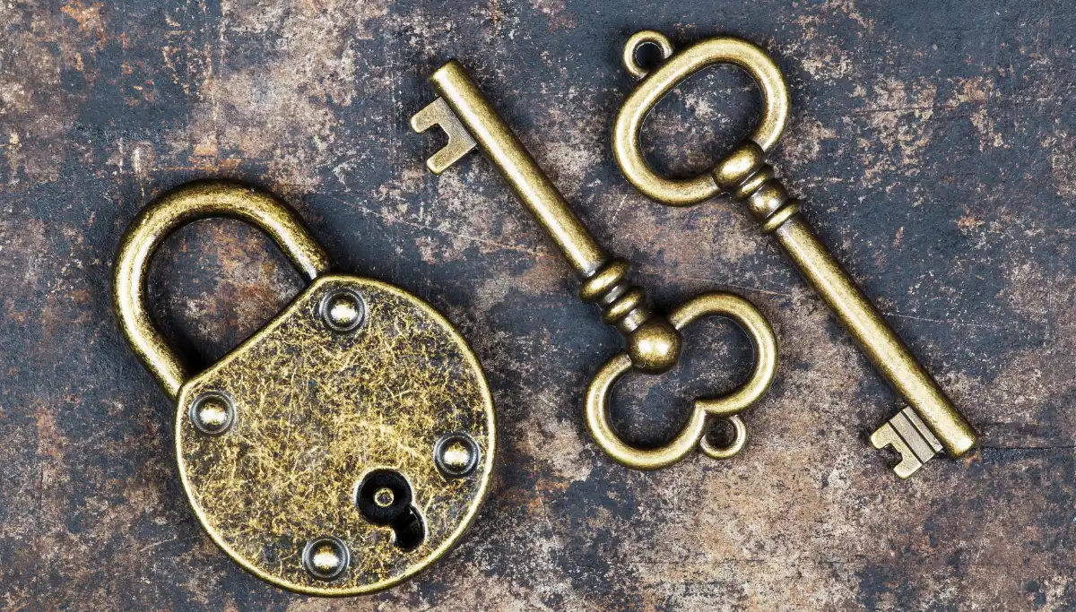 Vintage brass padlock and skeleton keys on a dark surface