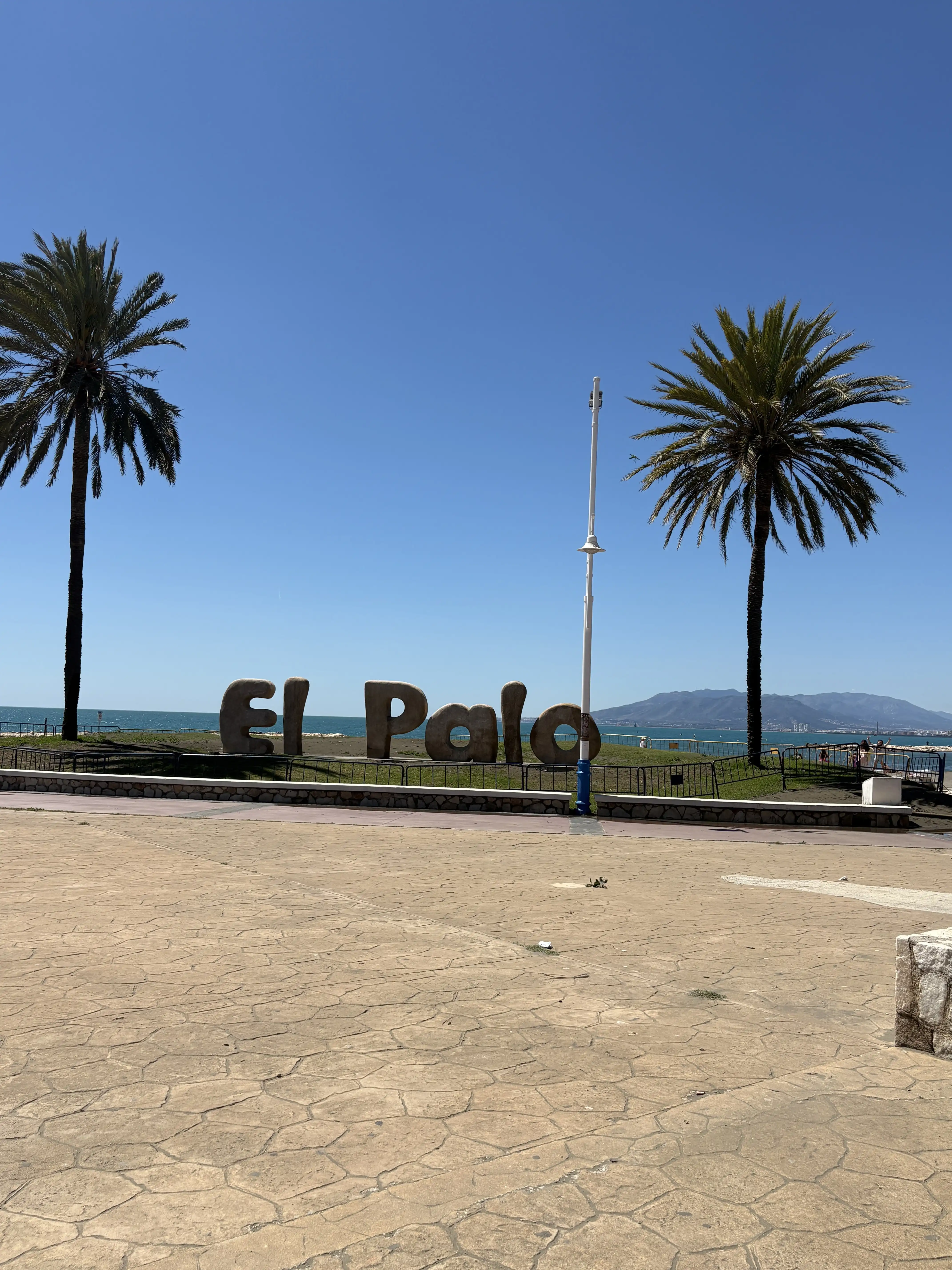 El Palo beach sign in cement under palm trees in Malaga