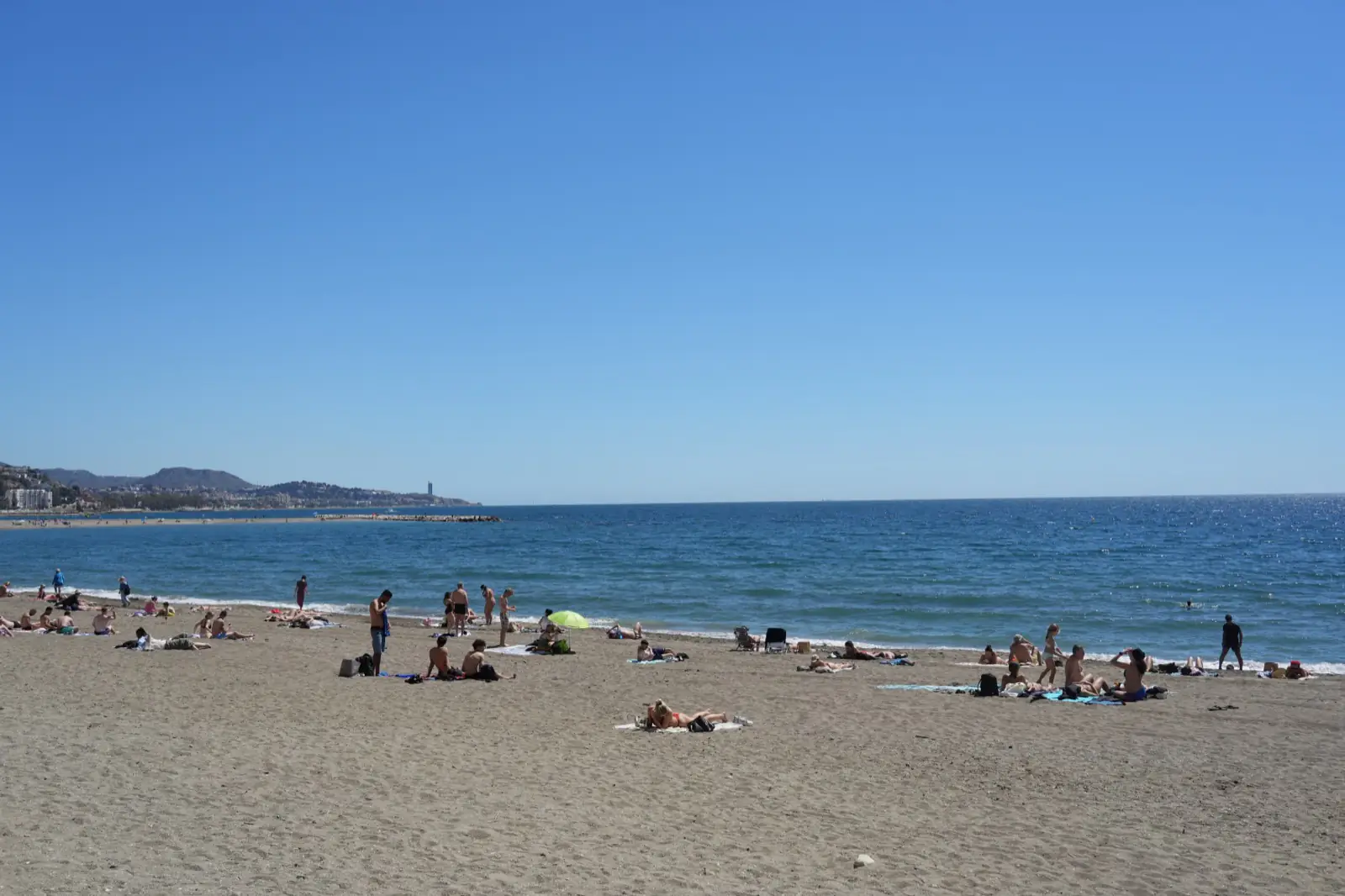 People relaxing on Malagueta beach on a warm spring day