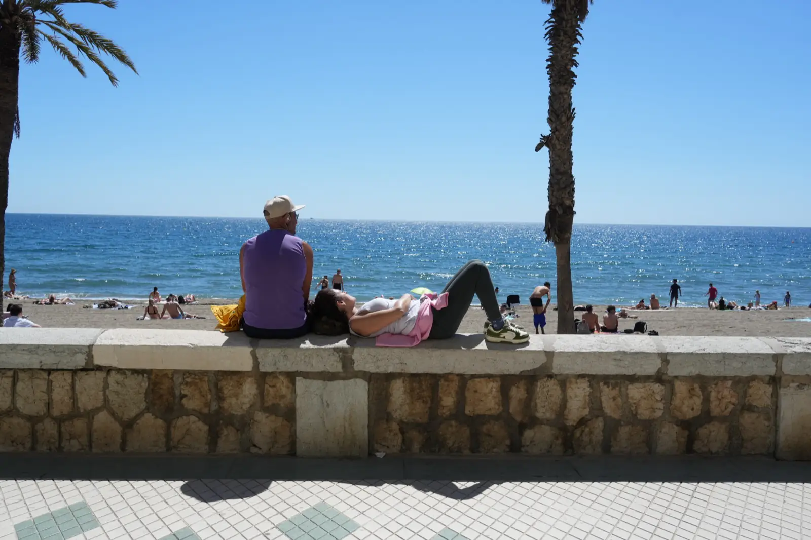 People resting on the Malagueta promenade in the morning