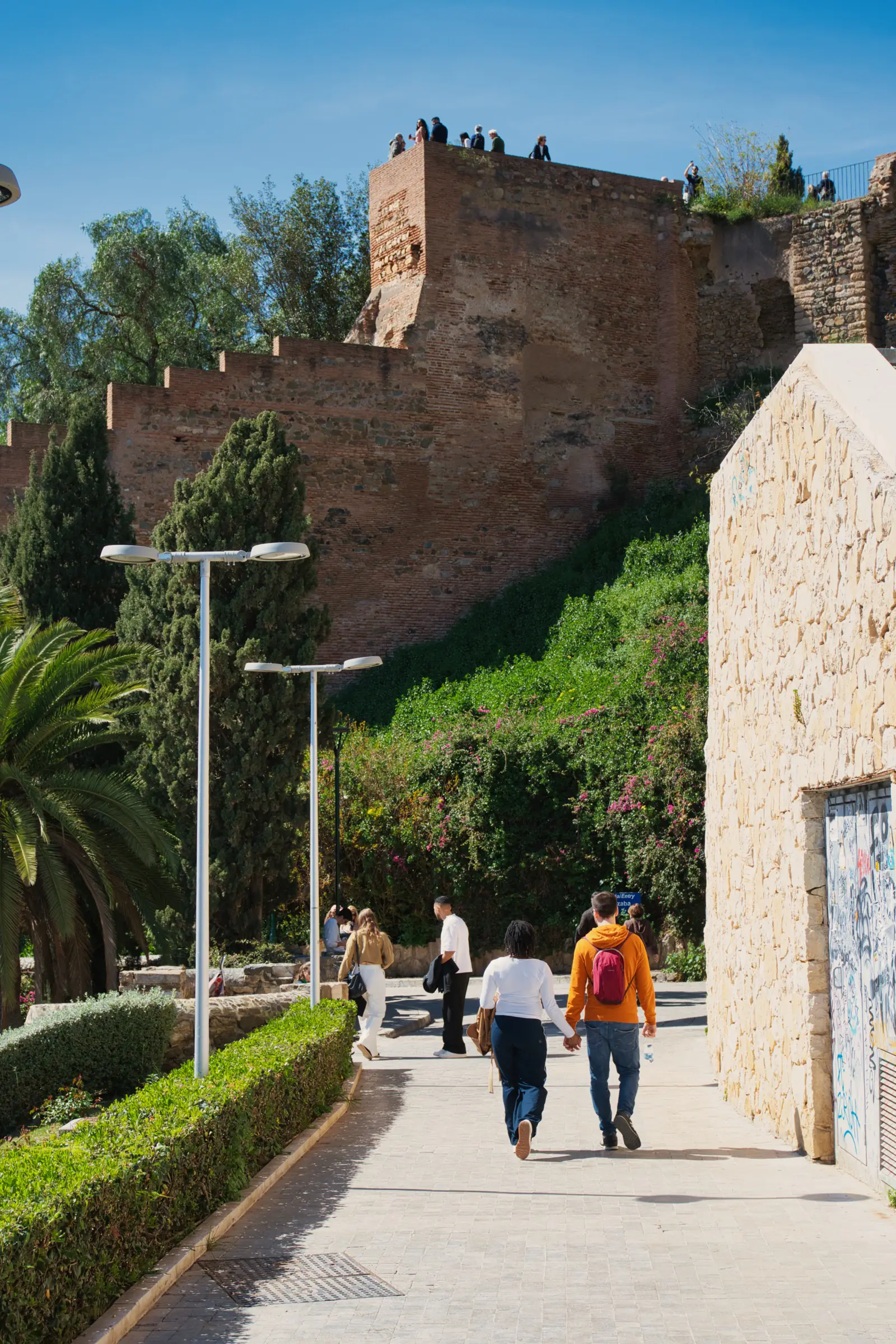 People walking along the path below the Alcazaba walls in Malaga