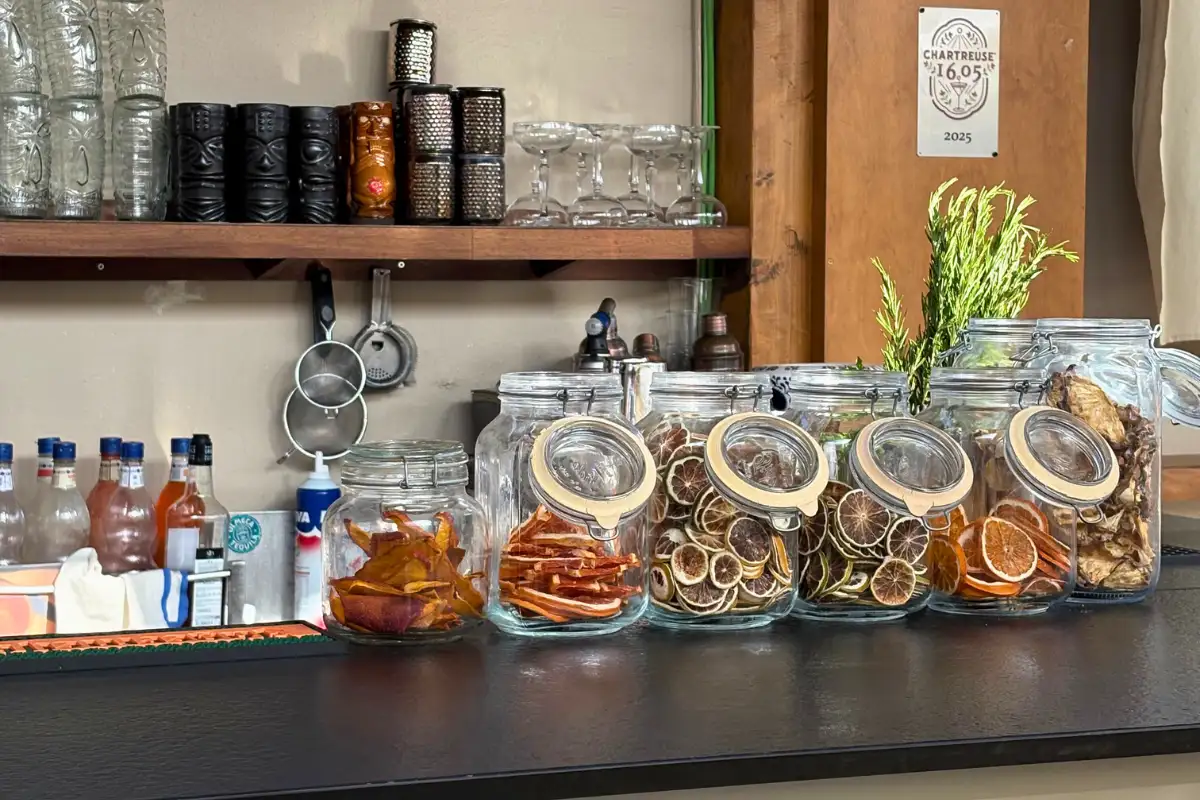The bar at Terraza Oasis in Malaga, with glass jars of dried citrus and herbs lined up on the counter and glassware on the shelves above