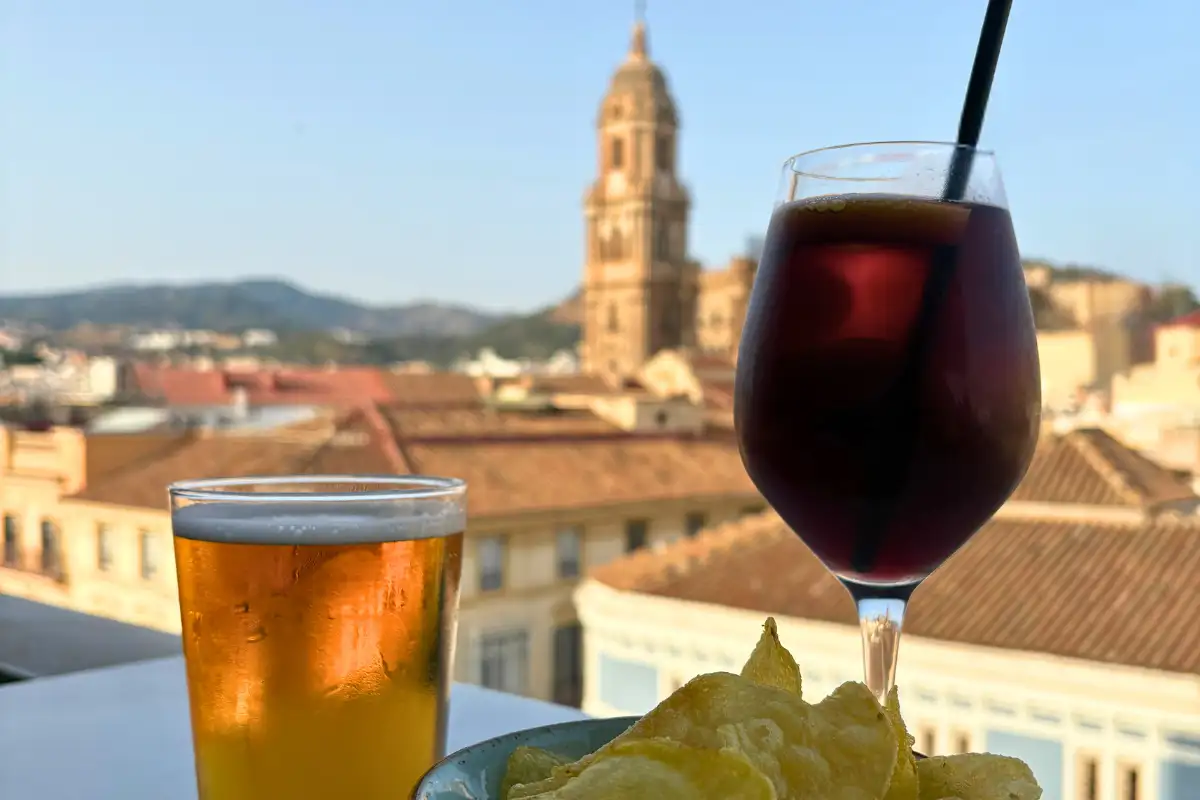 A beer and a tinto de verano on a table at Vincci Diez Larios rooftop, with Malaga Cathedral tower and old town rooftops in the background