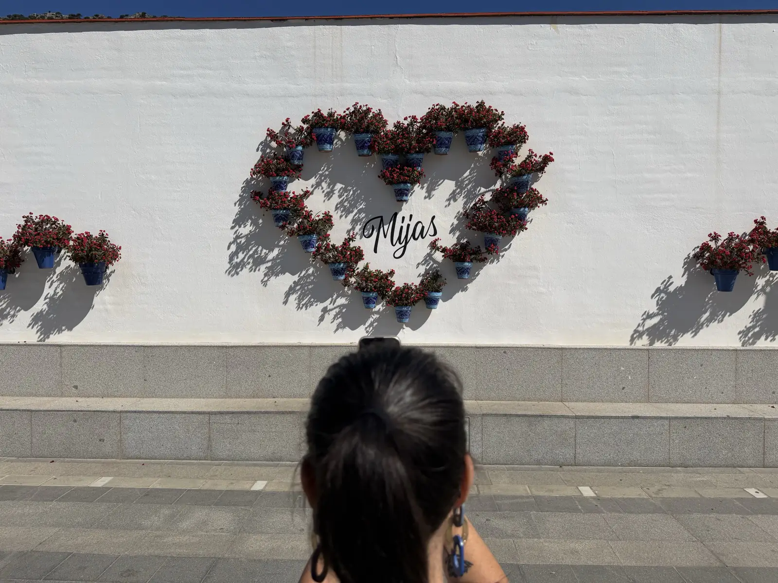 Heidi taking a photo of the heart made from flowers at the entrance to Mijas Pueblo