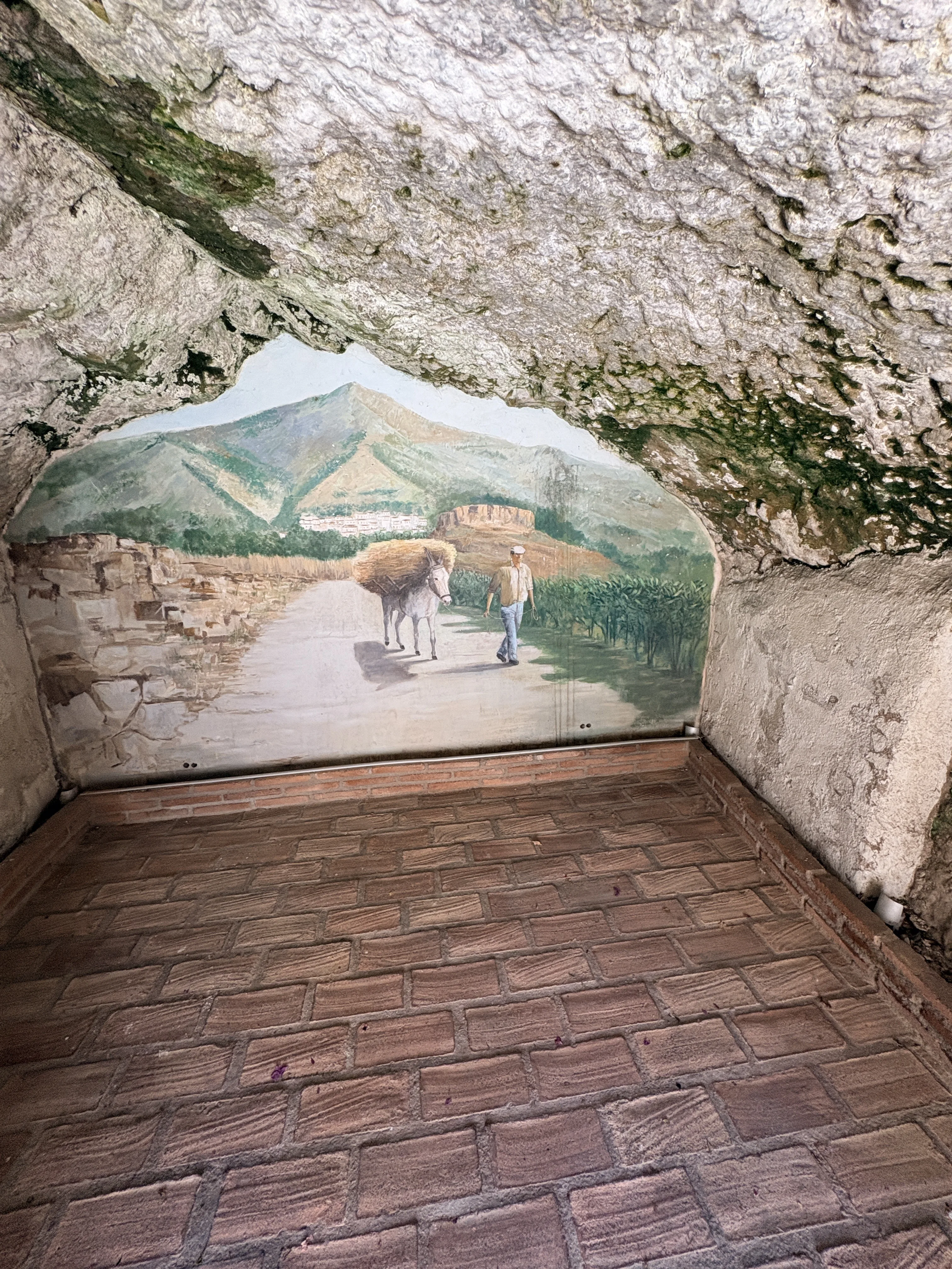 Landscape painting set into a rocky cave alcove in Mijas