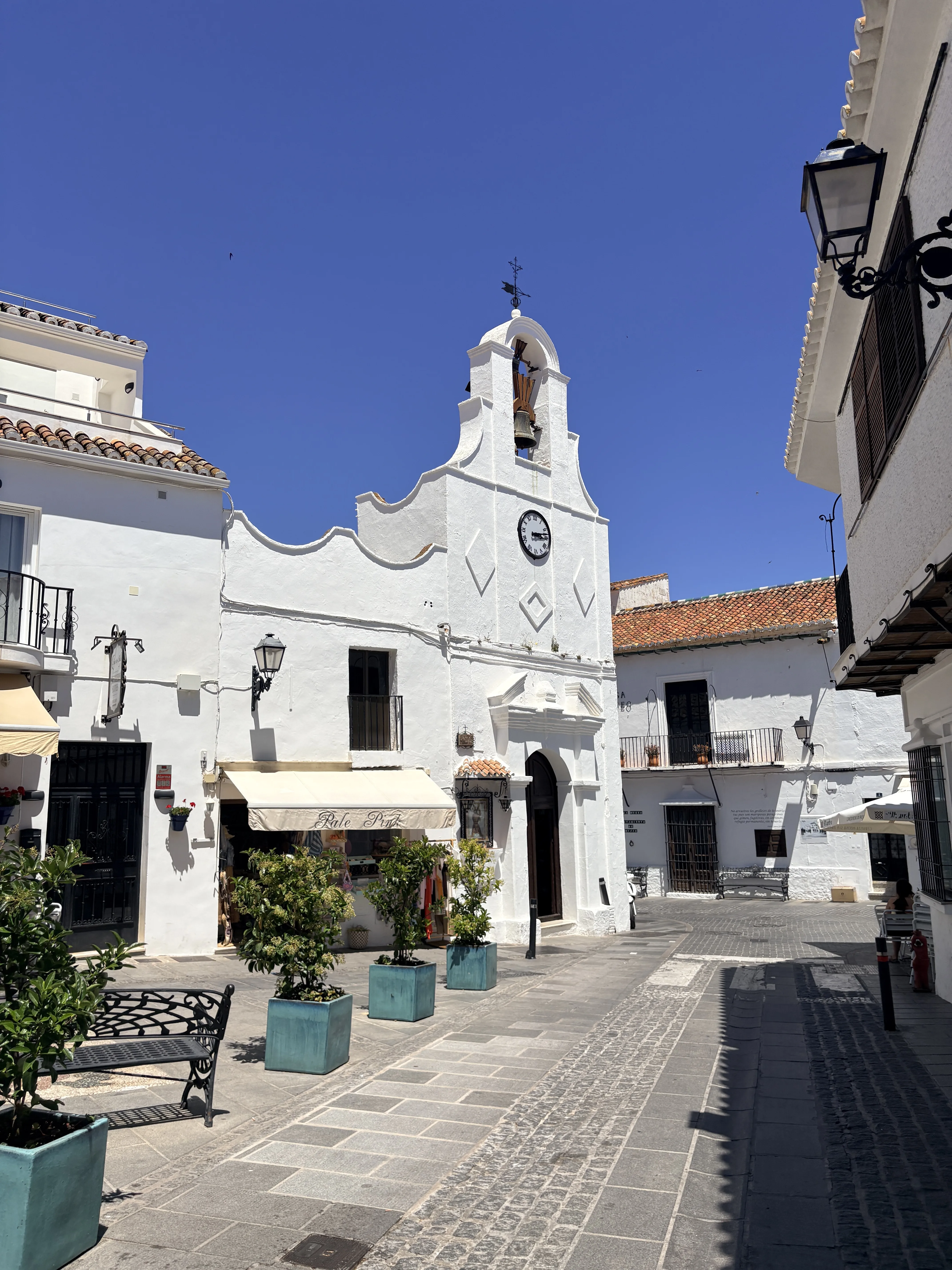 Church bell tower rising against a clear blue sky in Mijas