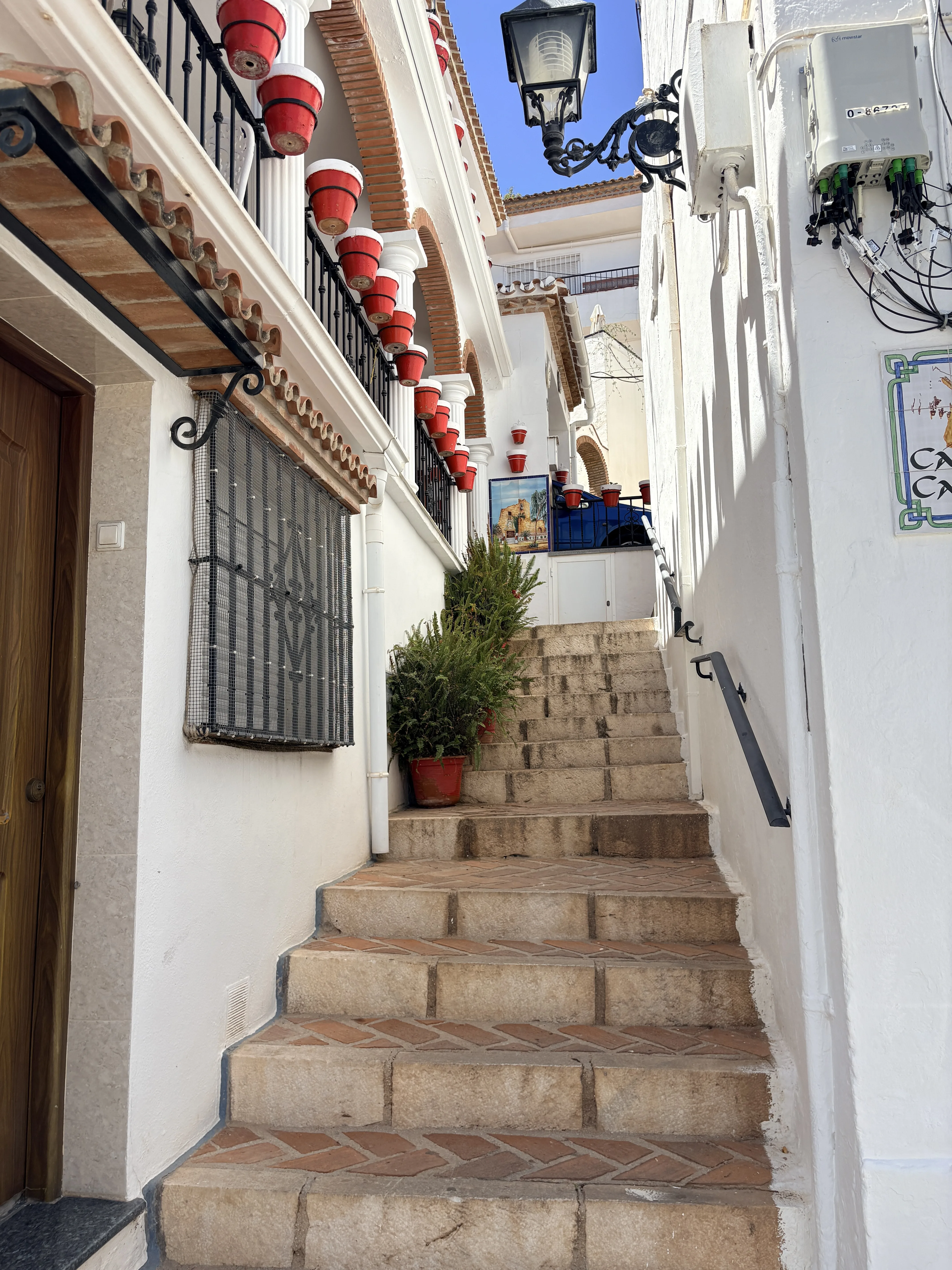 Ornate balcony with terracotta tiles and flower pots in Mijas