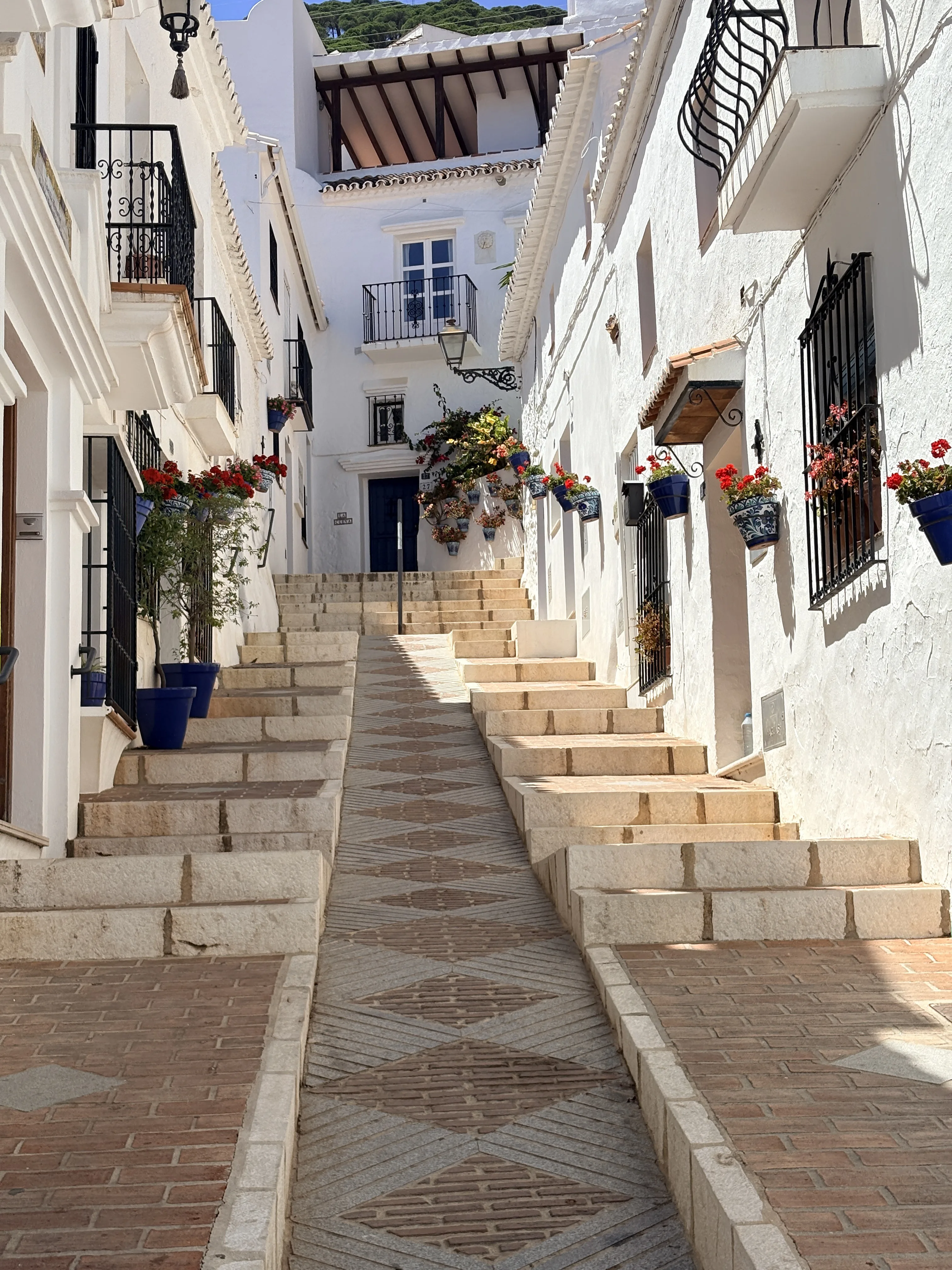 Street in Mijas with decorative tiled columns and terracotta flower pots