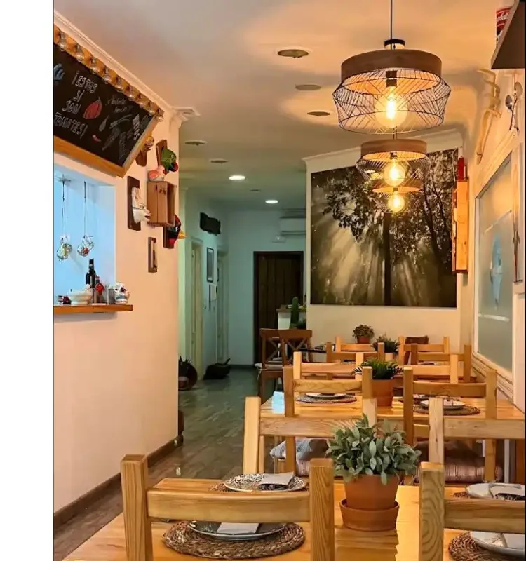 The warm interior of a restaurant in Mijas Pueblo with wooden tables and pendant lighting