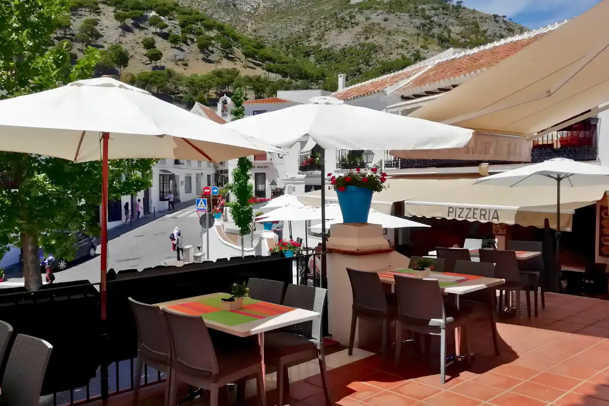 Restaurant terrace in Mijas Pueblo with white umbrellas and mountain views behind