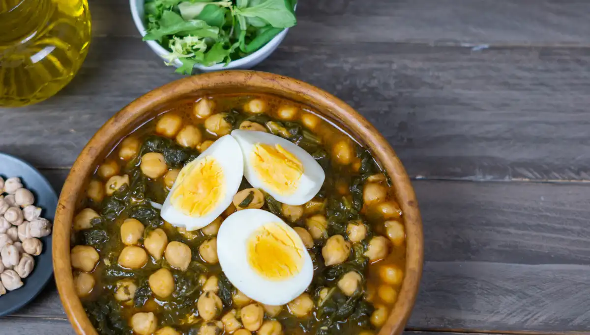 Bowl of espinacas con garbanzos topped with boiled egg, a classic Seville dish